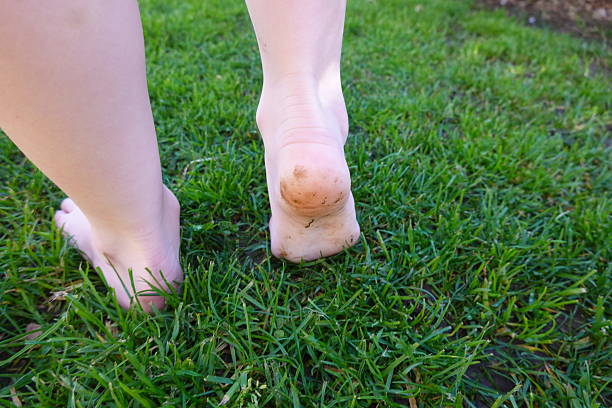istock Barefoot child walking on green grass with dirty heels 2205439985