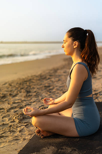istock Young woman meditating on the beach at sunset, finding inner peace and mindfulness 2205440742