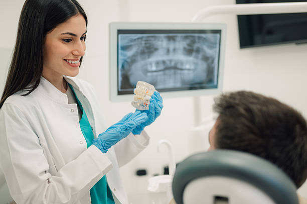 istock Dentist showing teeth model to patient in modern clinic 2205440972