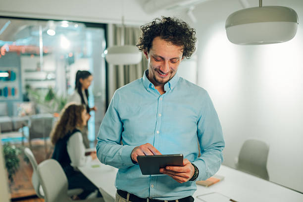 istock Smiling businessman using digital tablet in modern office 2205441247