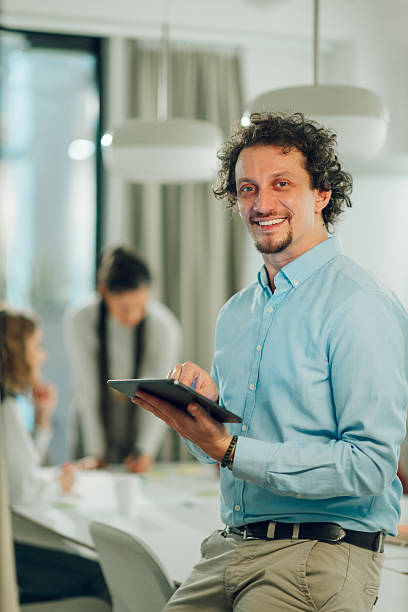 istock Smiling businessman using digital tablet during office meeting 2205441250