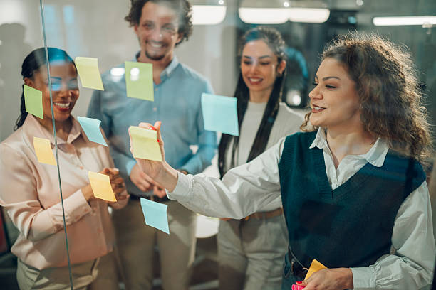 istock Business team sharing ideas using sticky notes on glass wall in office 2205441254