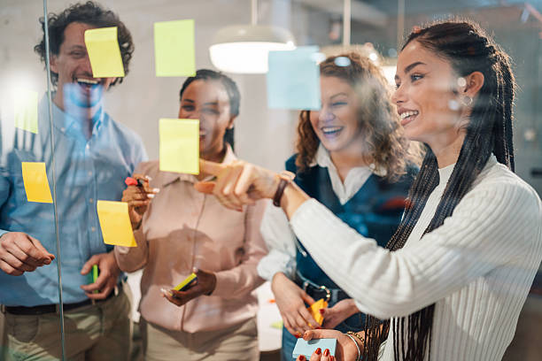 istock Smiling business team brainstorming with sticky notes on glass wall in office 2205441261
