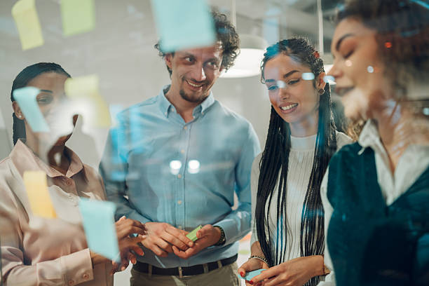 istock Business team sharing ideas using sticky notes on glass wall in office 2205441269