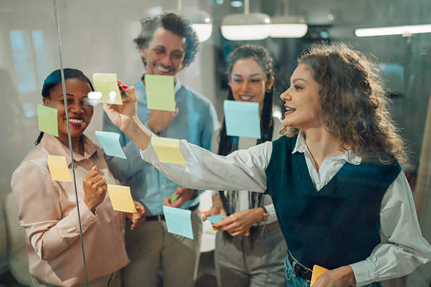 istock Business team brainstorming and planning using sticky notes on glass wall in office 2205441278