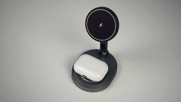 istock Wireless headphones are placed on a magnetic charging station. Wireless charging on a white table. 2205442199