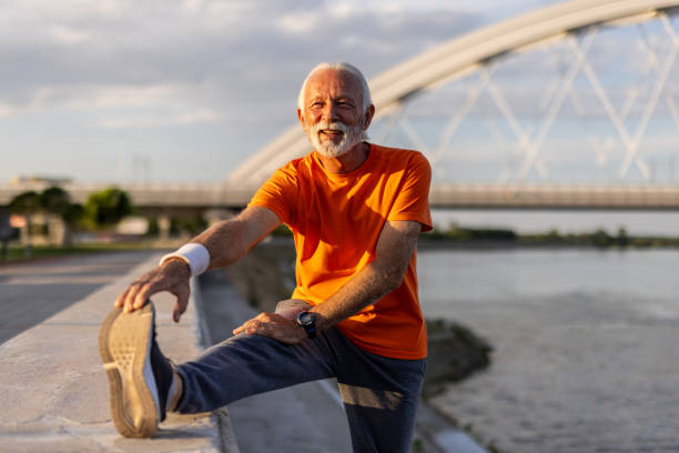 istock Senior man stretching legs before running near river 2205442813