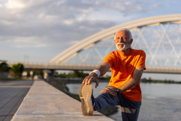 istock Senior man stretching legs after running near river and bridge 2205442816