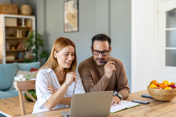 Couple working at home, using laptop and looking at finances