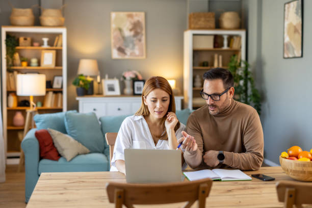 istock Focused couple discussing work at a computer in cozy room. 2205446557