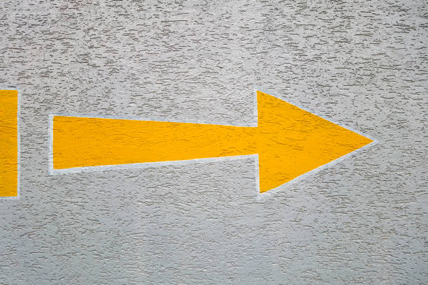 istock Yellow arrow sign painted on concrete wall. 2205446714