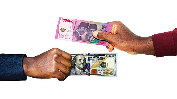 istock Indonesian rupiah USA Dollar currency pairing.Black African hands holding exchanging comparing  two  bank notes. indonesia versus USA. Weighing Currencies against each other. Exchange rate 2205453621