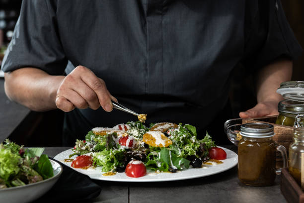 istock Chef garnishing a fresh, healthy salad on a white plate 2205457012