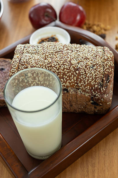 A simple and wholesome meal featuring a glass of fresh milk, a slice of soft bread, and a crisp apple, offering a balanced and refreshing start to the day.