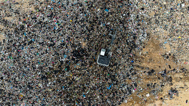 istock Garbage dump pile in trash dump or landfill, Landfill with waste disposal, Garbage truck unloads rubbish in landfill, Truck waste dump waste from household, Excavator work garbage waste, Aerial view. 2205459767