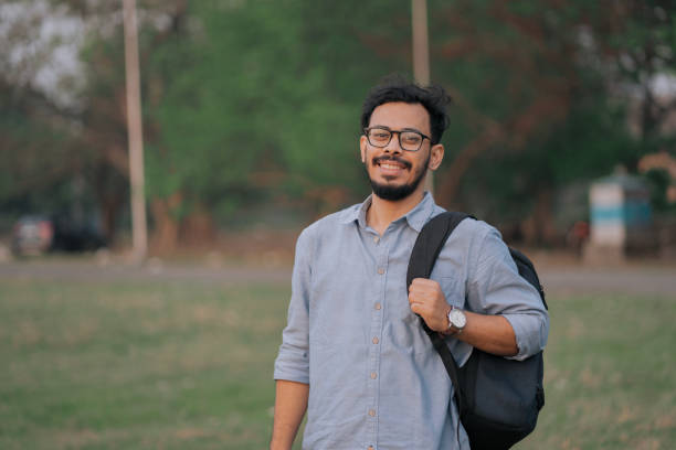istock Smiling Young Man with Backpack in Outdoor Park Setting 2205464543