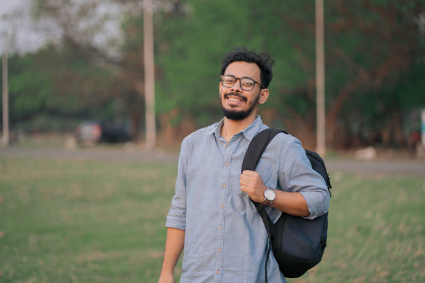 istock Smiling Young Man with Backpack in Outdoor Park Setting 2205464547