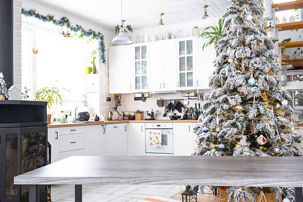 istock Grey Wooden empty table to demonstrate product with space for text with upholstered chairs in white kitchen, modern interior with Christmas tree and fairy lights. New Year, Christmas mood, cozy home. 2205470843