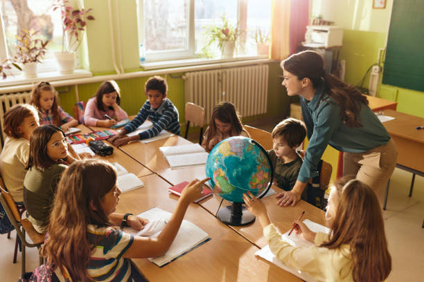 istock Happy teacher having geography class with her students at school. 2205473534