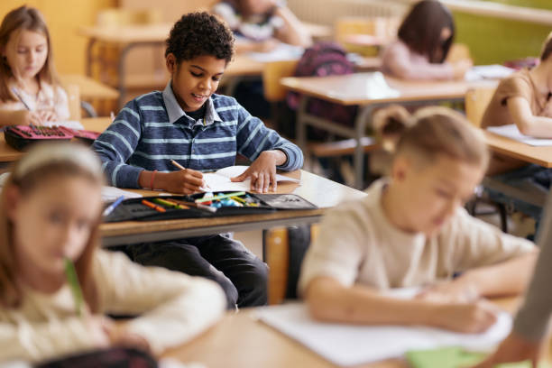 istock Happy black student writing on a class in the classroom. 2205474300