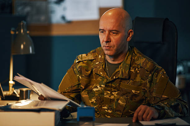 istock Soldier Sitting at Desk Reading and Writing Documents 2205475244