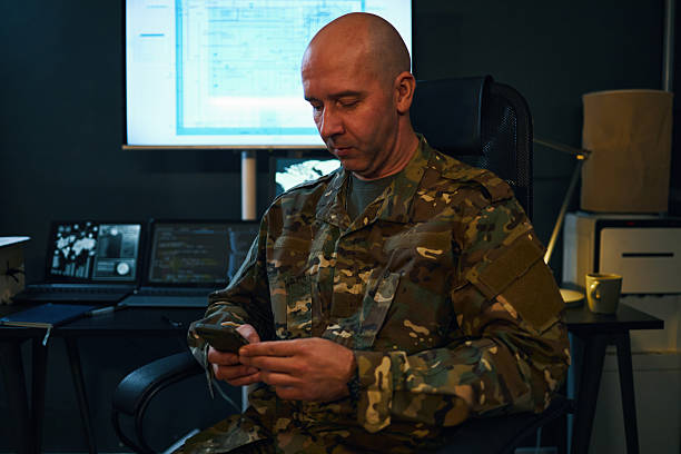 istock Soldier in Camouflage Uniform Sitting in Office Setting 2205475514