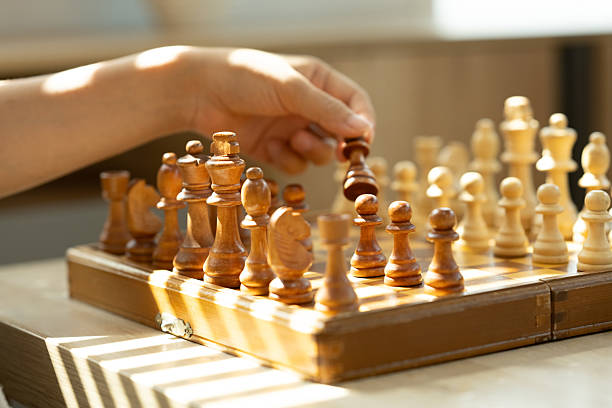 istock Hand holding chess piece, making a move on a classic wooden chessboard 2205476282