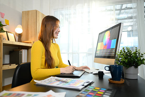 lächelnde frau, die an digitalen illustrationen oder designprojekten auf ihrem desktop-computer arbeitet. - grafiker stock-fotos und bilder