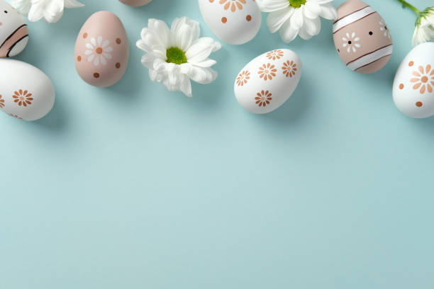 istock Easter eggs with floral patterns and daisies on a soft blue background. Flat lay, top view. 2205477096