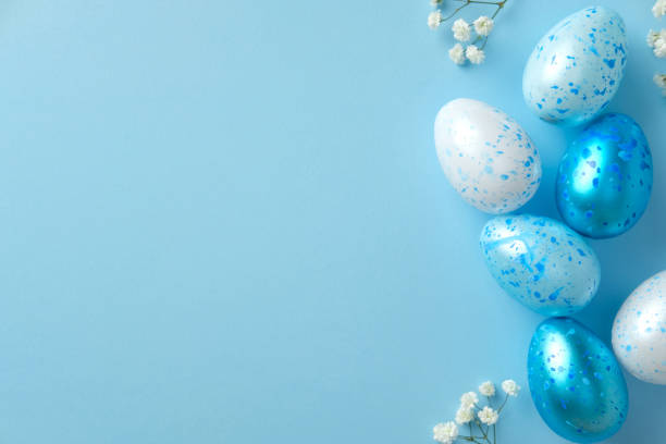 istock Aesthetic Easter flat lay composition with blue and white speckled eggs and small flowers on a light blue background. 2205477132