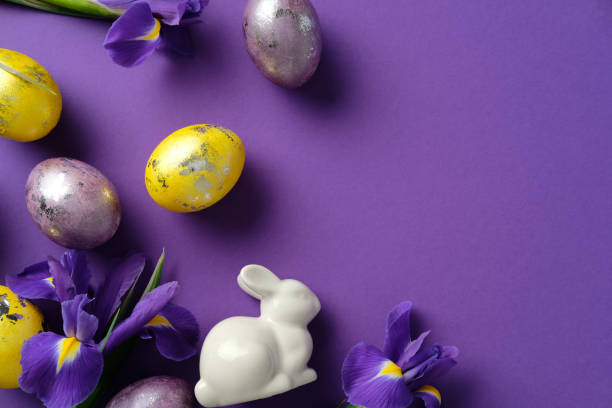 istock Easter flat lay composition with painted eggs, a white ceramic bunny, and purple irises on a vibrant purple background 2205477393