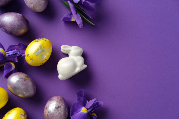 istock Easter flat lay composition with painted eggs, purple irises, and a ceramic bunny on a purple background 2205477408