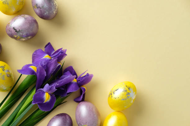 istock Flat lay yellow and purple Easter eggs painted with metallic effect, and fresh purple irises on a yellow background. Happy Easter greeting card design. 2205477596