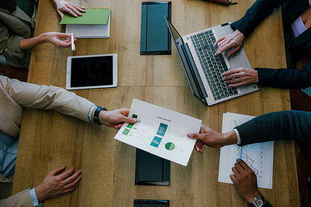 istock Business people exchanging documents with charts and graphs during meeting 2205477976