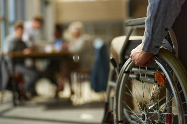 Close up of unrecognizable businessman in a wheelchair coming to a meeting in the office.