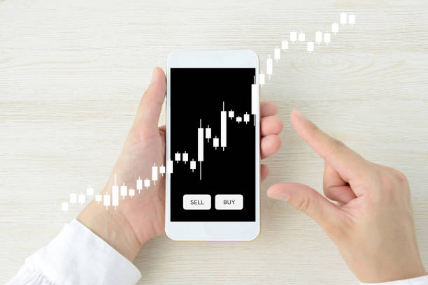 istock Investor’s hand and smartphone with stock chart 2205478669
