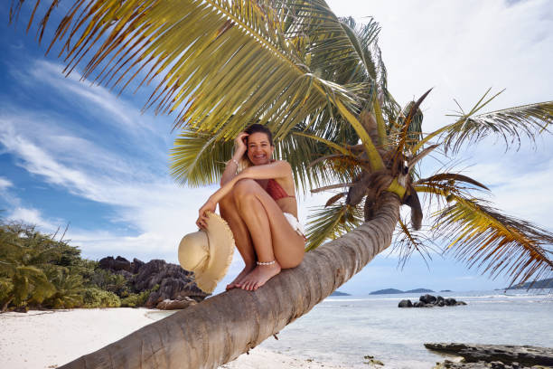 istock Young happy woman enjoying on a palm tree at the beach. 2205479355