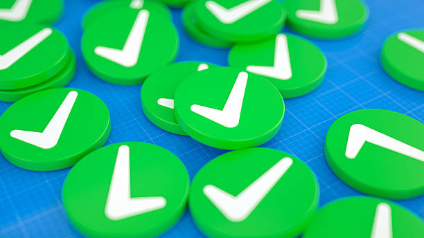 A pile of green circular tokens featuring white check marks, rendered in 3D on a blue grid background. Represents concepts like approval, success, validation, confirmation, completion, correctness, agreement, and positive results.