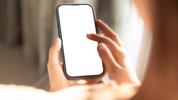 istock Close up of Woman hand holding using touch mobile phone white screen mockup. Back view 2205487605