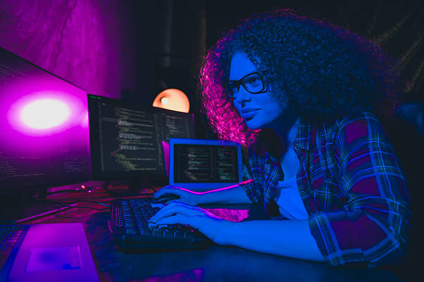 istock Young professional woman programming at a workstation illuminated by neon glowing lights. 2205489145