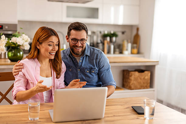 istock A happy couple working together on a laptop while reviewing documents. They share a moment of collaboration and planning, enjoying a productive and positive atmosphere in their well-lit living space. 2205491748