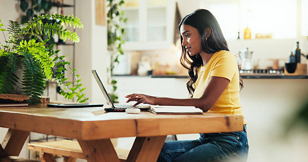 istock Woman, student and typing with laptop in kitchen for online course, elearning or class schedule at home. Female person, studying and distance learning with computer for remote education or assignment 2205492229
