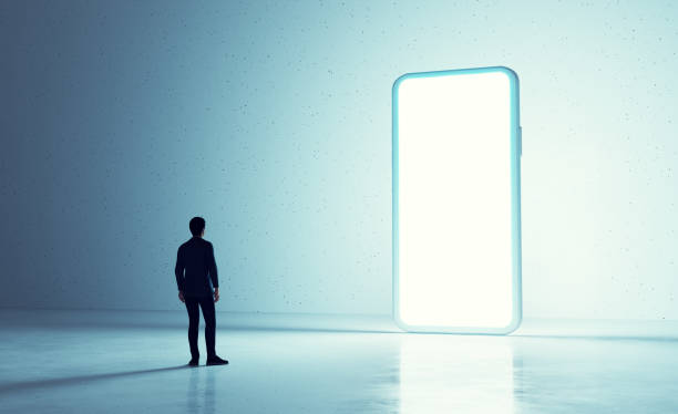 istock Man looking at big glowing smartphone screen contemplating possibilities with digital technology 2205492306