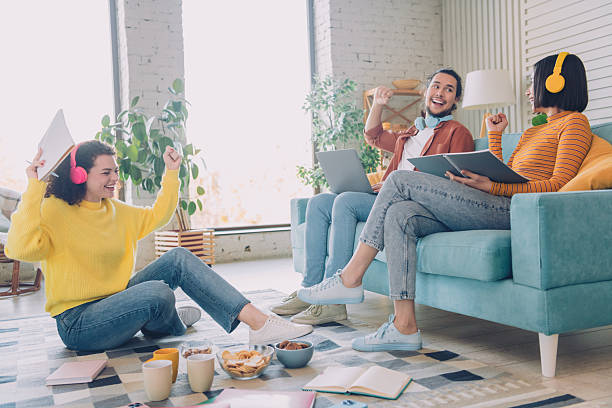 istock Happy young friends relaxing together at home, enjoying casual conversations and using electronic devices 2205492430