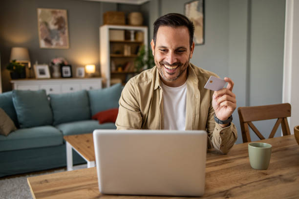istock Happy man making online payment using credit card and laptop at home 2205493597