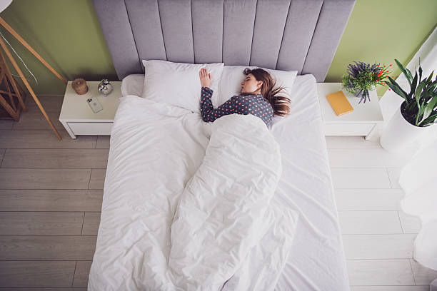 istock Young woman sleeping peacefully in a comfortable bed surrounded by modern bedroom decor and natural daylight. 2205493777