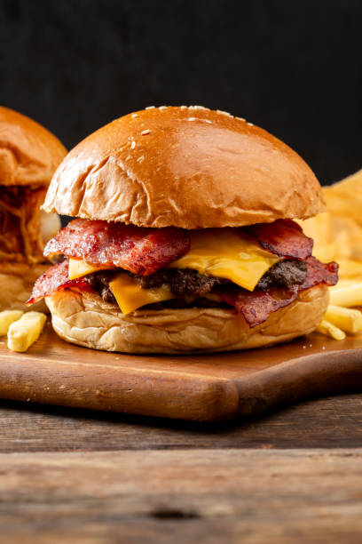 istock Juicy Cheeseburger with Crispy Bacon and Fresh Ingredients on a Wooden Board 2205495250