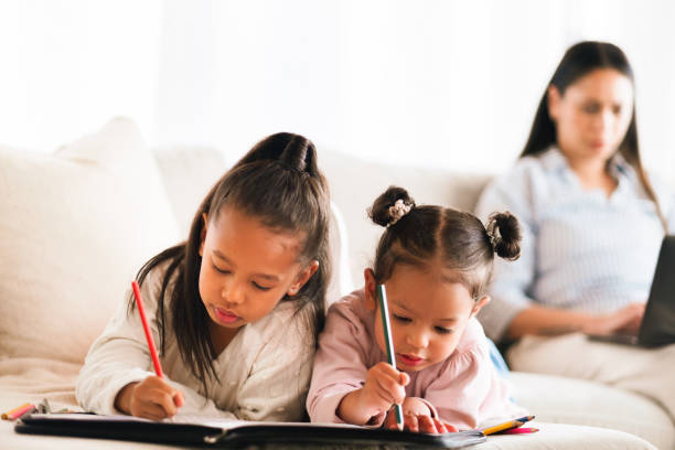 istock Education, sisters and children writing on sofa in home school for creative development, color and study. Girls, siblings and drawing with paper for art, homework and student learning with mother 2205496087