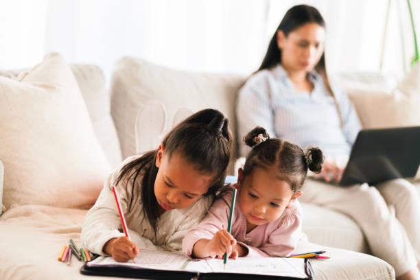 istock Education, sisters and kids color with mother in home for creative skill, development or study. Girls, siblings and drawing with paper in living room to help with art, homework or learning together 2205496095