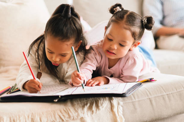 istock Education, sisters and kids drawing in home school for creative skill, development or study. Girls, siblings or color with paper on living room sofa to help with art, homework or learning with family 2205496117